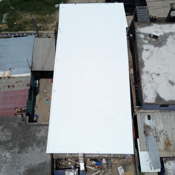 Vista aérea de un edificio largo con impermeabilizante acrílico blanco recién aplicado